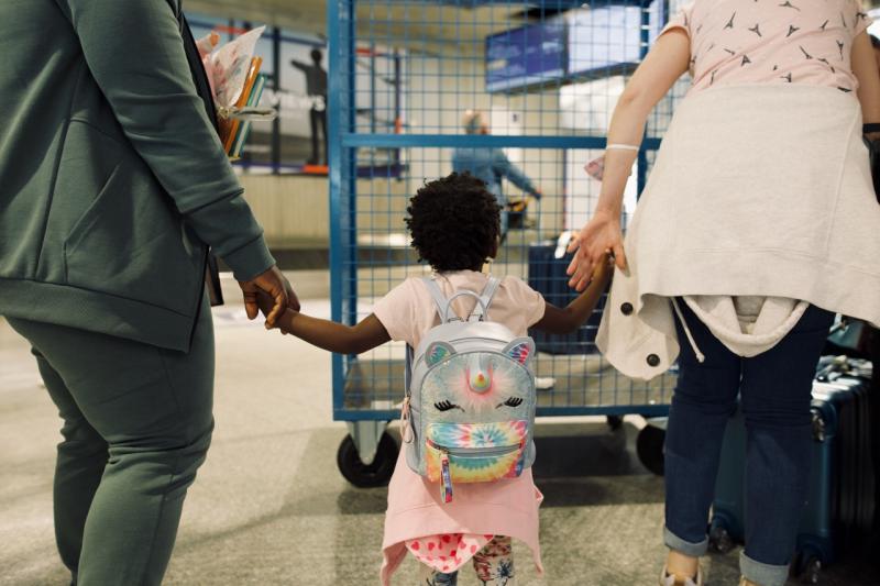 Image of a little girl holding the hands of two adults, after she just reunited with her mum